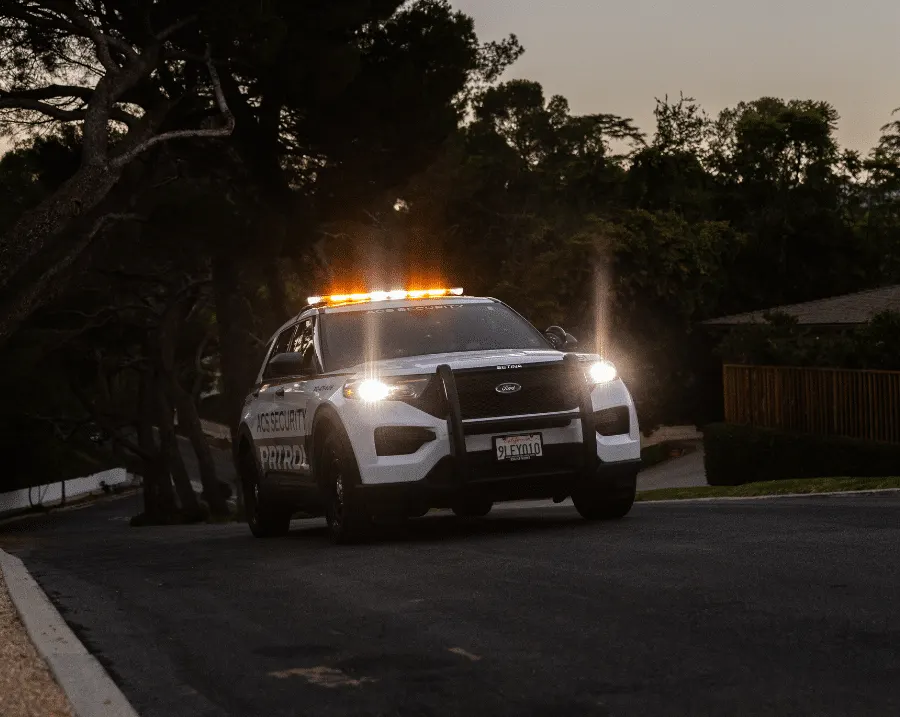 ACS Security patrol vehicle on a tree-lined residential street at dusk